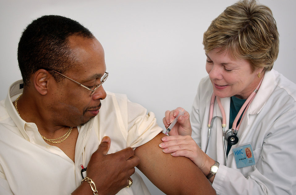 A nurse giving a middle aged man a vaccination shot.